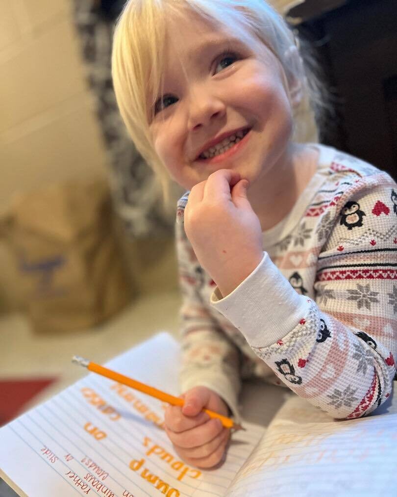 Preschool girl writing in her journal and smiling